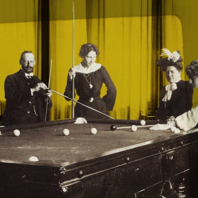 Kuvassa kolme naista ja yksi mies pelaavat biljardia 1800-luvulla.