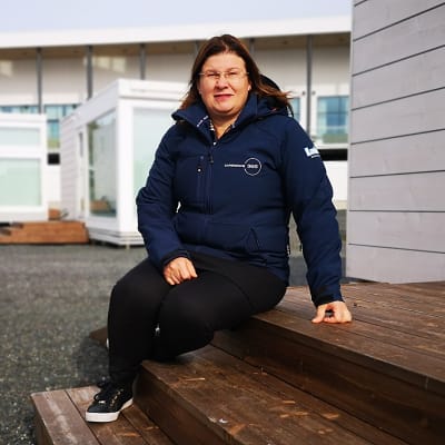 Kemin Matkailun toimitusjohtaja Susanna Koutonen istuu lumilinna-alueen lasivillan portailla.
