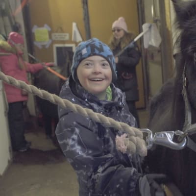 Tioåriga Lenni står glad tillsammans med en häst 