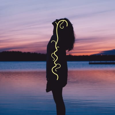 Nainen seisoo rannalla siluettina. Hänen kehossaan kulkee vagus-hermo keltaisena juosteena.