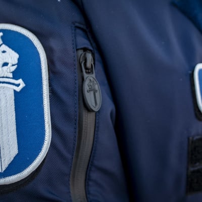 Närbild av polis i uniform. Texten poliisi polis syns på bröstet och på överarmen finns polisens emblem bestående av ett svärd och ett krönt  lejonhuvud.
