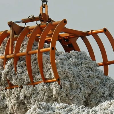 En stor orange griplastare lyfter fluffig grå råbomull.