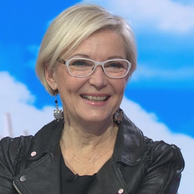 Ex-uutisankkuri Pirjo Nuotioi hymyilee Puoli seitsemän -ohjelman pinkillä sohvalla. 