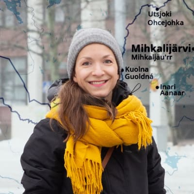 Saamelainen Laura Feodoroff seisoo ulkona Helsingissä talvivaatteet päällään. Taustalla näkyy kartta Pohjois-Suomesta.
