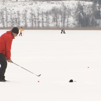 Mies pelaa golfia jäällä.