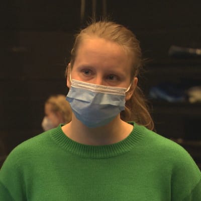 Charlotta Ingraeus i förgrunden med ansiktsskydd. I bakgrunden sitter ljudtekniker.