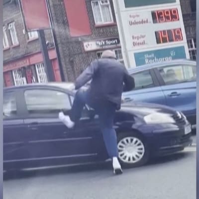 Mies potkii autoa bensa-asemalla Englannissa.