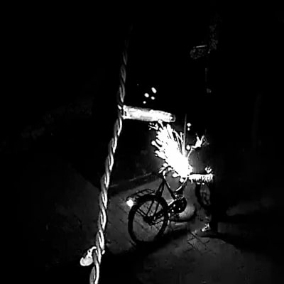 En tjuv söndrar ett cykellås med en batteridriven vinkelslip på natten.