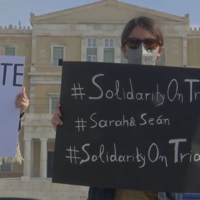 Demonstrerande flickor bär på plakat i Aten i protest mot rättegång på ön Lesbos i Grekland