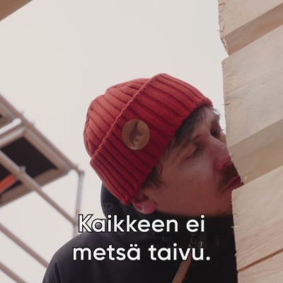 Toimittaja Tuukka Pasanen haistaa rakennettavan puutalon seinää.