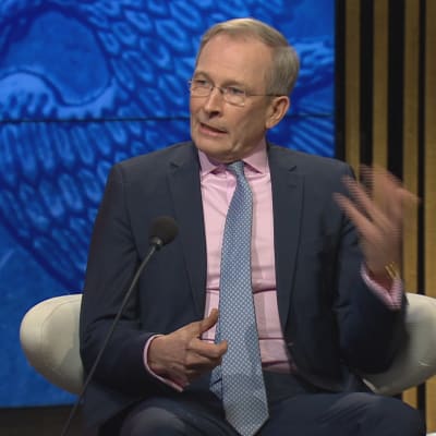Risto E.J. Penttilä gestikulerar stort i TV-studion. 