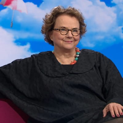 Professori Laura Kolbe istuu Puoli seitsemän -ohjelman pinkillä sohvalla.