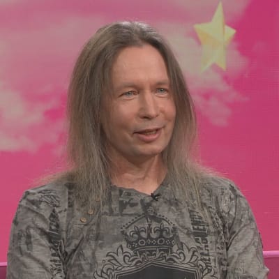 Stratovarius-yhtyeen keulahahmo Timo Kotipelto Puoli seitsemän -ohjelman studiossa istumassa pinkillä sohvalla. 