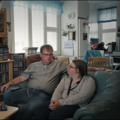 Två personer, Anders och Cecilia, sitter bredvid varandra i en mörkgrön lädersoffa.