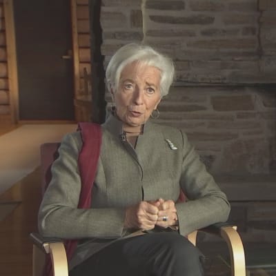 Christine Lagarde i en fåtölj framför en brasa.