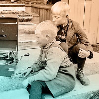 Kaksi pikkupoikaa kuuntelee gramofonia tuvan rappusilla noin 1930-luvulla.