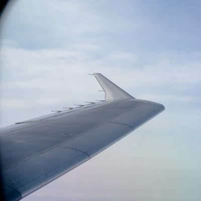 En flygplansvinge fotograferad från ett flygplan i luften.