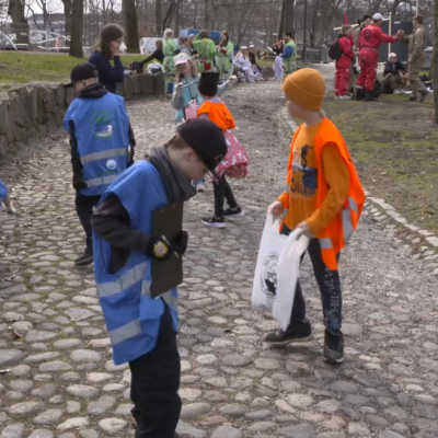 Barn med soppåsar samlar skräp.