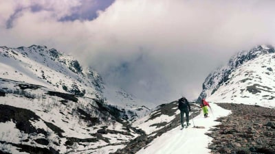 Skidåkare på väg upp till en bergstopp.