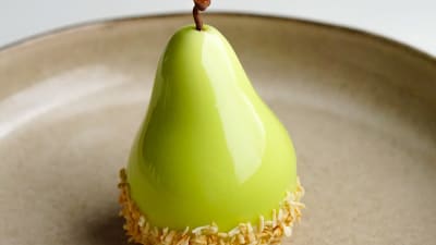 Ett glansigt, grönt bakverk format som ett päron.
