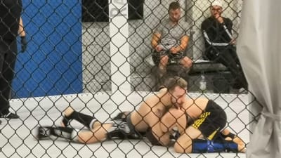 Två män ligger på golvet och kämpar mot varandra i MMA