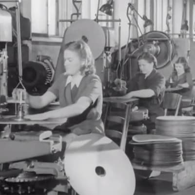Kvinnor arbetar vid maskiner i en fabrik.