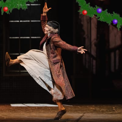 Saiturin joulu -baletin päähenkilö Scooge (Antti Keinänen) kävelee suurieleisesti sivuprofiilissa siten, että jalka nousee rinnan korkeudelle ja kädet ovat levällään.