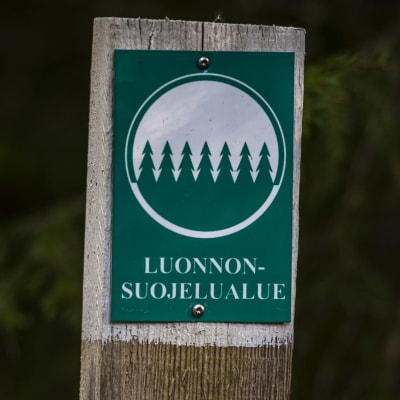 En skylt med texten "Luonnonsuojelualue" (naturskyddsområde).