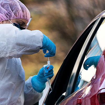 Mehiläisen drive-in-koronaviruksen testauspiste Espoon Tapiolassa 19. maaliskuuta . Työntekijä ottaa testiä autossa istuvalta.