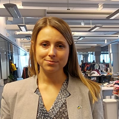 Kvinna står framför högar med kläder.