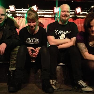 punk-yhtye istuu lavan reunalla.