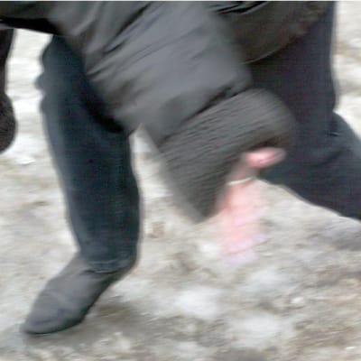 En kvinna faller omkull på en hal trottoar.