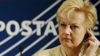 Suvi Lindén sitter bredvid två män i kostym.