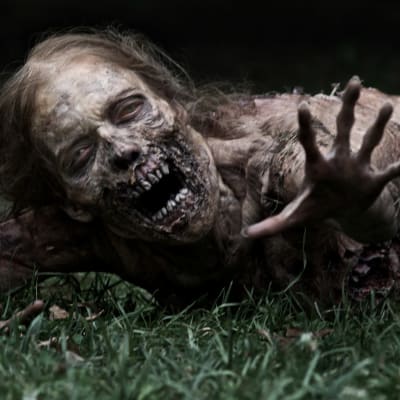 En zombie på marken sträcker ut handen i tv-serien The Walking Dead.