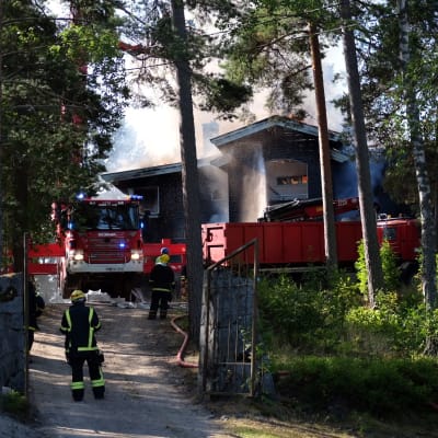 Ett hus som brinner som brandmän försöker släcka.