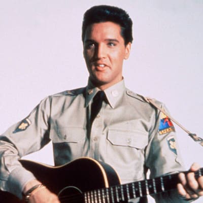Elvis Presley bär militäruniform och spelar akustisk gitarr.