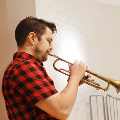 Trumpetisti-säveltäjä Verneri Pohjola soittaa trumpettia porraskäytävän ylätasanteella.