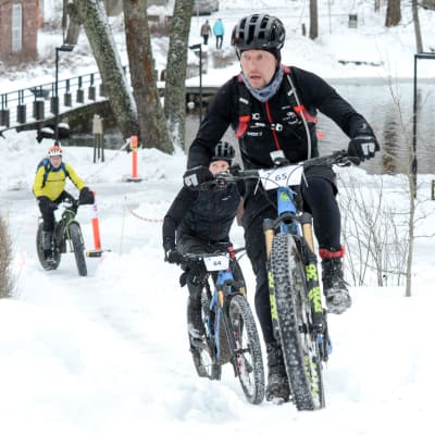 Tomi Paavola cyklar i vinterräng upp för en backe.