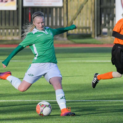 En ung kvinna i vita shorts och grön tröja spelar fotboll i Ekenäs IF. Hon heter Rebecka Mannström.