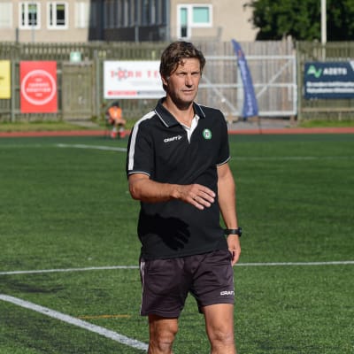 En person går vid en fotbollsplan.