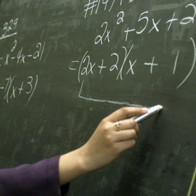 En lärare skriver matematiska formler på en tavla