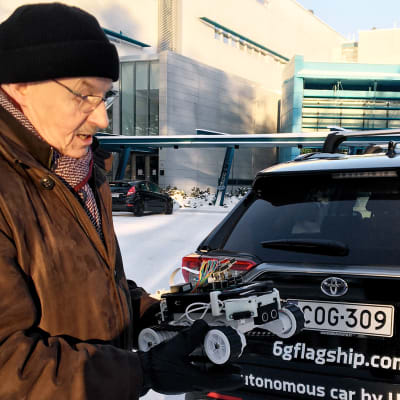 Emeritus professori Pasi Kuvaja esittelee &g tekniikalla toimivan auton pienoismallia.