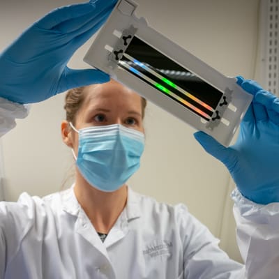 Tutkija Sari Hannula tarkastelee läpivirtauskammiota FIMMin laboratoriossa.