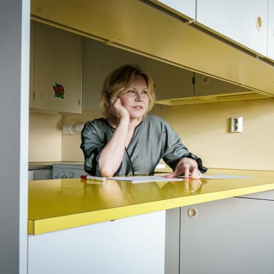 Arkkitehtiliitto SAFASn puheenjohtaja Henna Helander nojaa kyynerpäähänsäö keittiötason äärellä ja katsoo ulos ikkunasta.