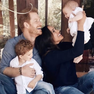 Prins Harry med hustrun Meghan och deras två barn. Archie sitter i pappas famn medan Meghan lyfter upp Lilibet i luften. Alla skrattar.