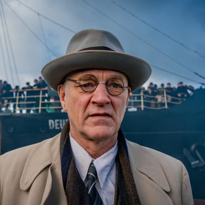 Ville Virtanen i rollen som Abraham Stiller stående frmaför ett fartyg med naziflagga i fören.
