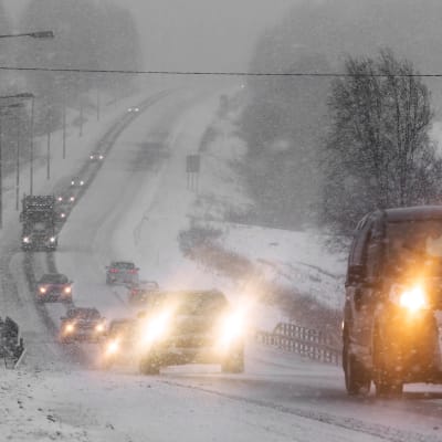 Autoja maantiellä lumisateessa.