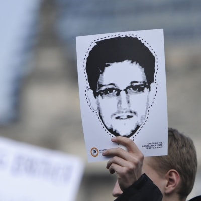 hand håller uppe Edward Snowden-bild som mask att klippa ut.