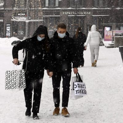 Promenerande människor i snöigt Helsingfors. 