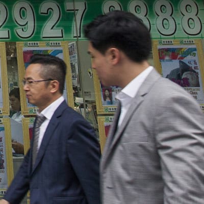 Två män framför en fastighetsförmedling i Hongkong.